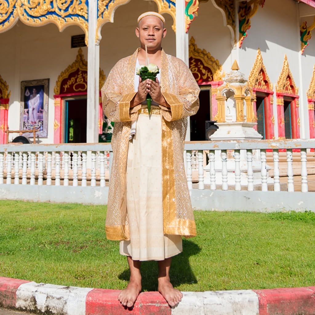 นาคในชุดพิธียืนถือดอกบัวหน้าพระอุโบสถ
