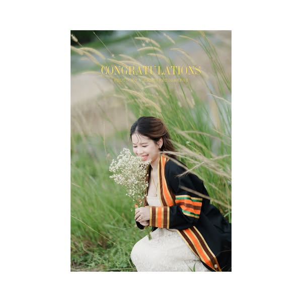 บัณฑิตหญิงถือช่อดอกไม้ในทุ่งหญ้าพร้อมตัวอักษรแสดงความยินดี