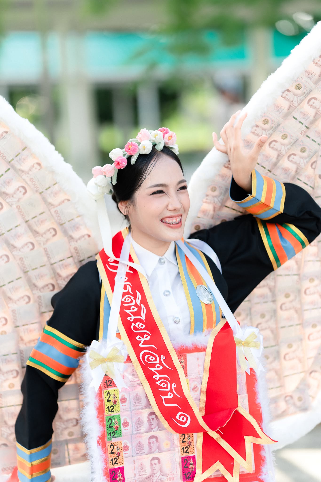 บัณฑิตหญิงยิ้มในชุดครุยพร้อมมาลัยธนบัตร
